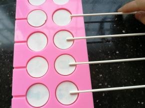 再放入棒棒糖棍子。重复步骤2、3、4、5继续熬煮另外250克珊瑚糖，同样也是加入25ml水煮，煮好后倒入已经放好图案的棒棒糖模具中至满模即可。