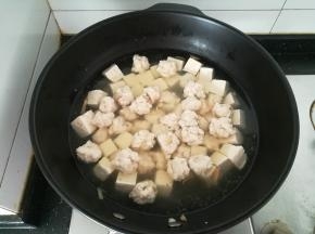 水开之后，用手把鱼泥挤成丸子，放入锅中。