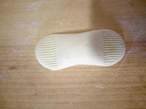 下面来做元宝，切一小块面团，搓长条两边用手压扁，再用干净的梳子压出花纹