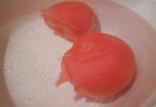 番茄切“十”子花刀，放入热水浸泡，泡至番茄开裂，去皮，切小块