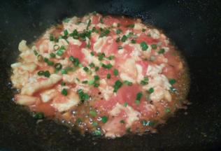 翻炒至番茄汤汁变少，放鸡蛋，把两者翻炒均匀，加少许盐提味，撒葱花