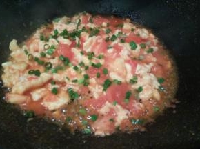 翻炒至番茄汤汁变少，放鸡蛋，把两者翻炒均匀，加少许盐提味，撒葱花