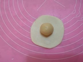 取一个松弛好的油皮面团，擀圆，放一个油酥。