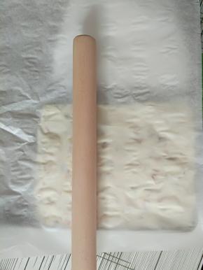 13.最后用擀面杖，铺上一张油纸，在糖上面轻轻擀几下，轻轻的哦，不然压实了等下糖粘住了烤盘挖不起来了。亲身经验～告诉小伙伴们哈！