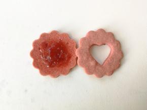 取一片圆形饼干，放上适量草莓酱，再盖上一片中间挖成心形的饼干，爱心夹心饼干就组装完成了