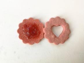 取一片圆形饼干，放上适量草莓酱，再盖上一片中间挖成心形的饼干，爱心夹心饼干就组装完成了