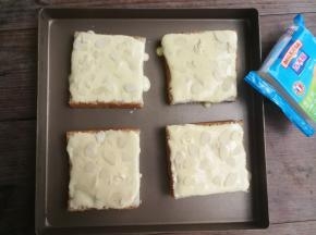吐司摆进烤盘，用勺子将制作好的面糊舀到吐司片上，用勺背抹匀，然后撒上杏仁片