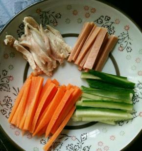 把胡萝卜、黄瓜和火腿肠切成小条。鸡腿肉也撕成条。