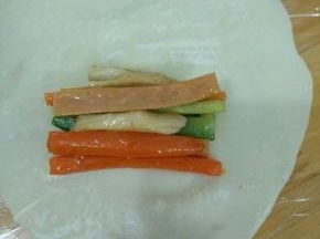 取一张饺子皮，用擀面杖擀大擀薄。放皮的三分之一处放上适量食材。