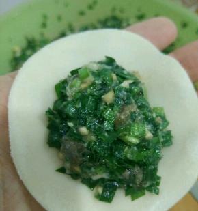 取一片饺子皮，放适量韭菜馅。