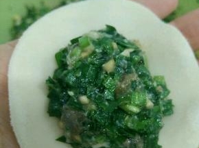 取一片饺子皮，放适量韭菜馅。