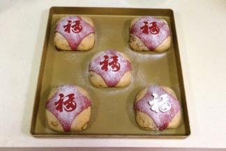 把裁剪好的“福”字小卡片放在红色小面片上，筛上少许高筋面粉，然后在把“福”字卡片轻轻拿起。