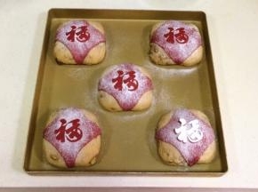 把裁剪好的“福”字小卡片放在红色小面片上，筛上少许高筋面粉，然后在把“福”字卡片轻轻拿起。