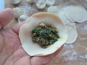 拿一个饺子片，放在左手手指上，放入适量的馅。