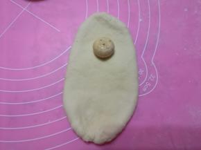 取一个小面团，擀成椭圆长片，放入一块姜糖。