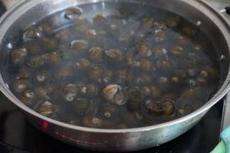 锅里的水烧开后，放入田螺，焯几分钟