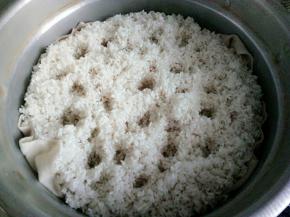 把米捞出来，放入蒸锅，然后在米上用手指扎些小洞，这样做的目的是为了让米更好的蒸熟蒸透