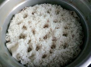 把米捞出来，放入蒸锅，然后在米上用手指扎些小洞，这样做的目的是为了让米更好的蒸熟蒸透