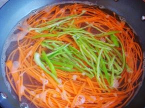 胡萝卜放入开水锅里烫软，最后放入青椒丝稍微烫一下捞出过凉水，沥干水份备用。