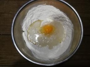 将泡打粉和盐放入面粉里，用筷子搅匀后加入鸡蛋、水和玉米油