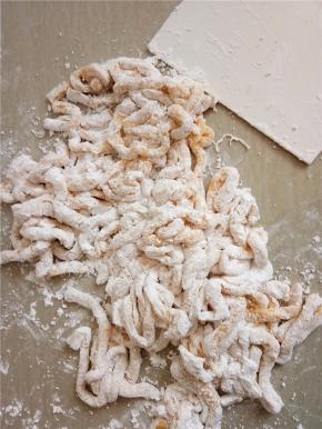 用刀将面皮切成条状，撒上玉米淀粉防粘。