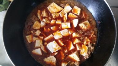 加入麻婆豆腐调料，以前都是自家辣椒、麻椒配，现在买现成的了，加入适量的水煮一下