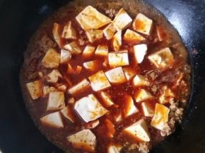 加入麻婆豆腐调料，以前都是自家辣椒、麻椒配，现在买现成的了，加入适量的水煮一下