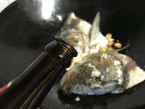 煎至两面呈金黄色，放入老姜和大蒜。再加入适量料酒去腥。