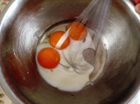 2．	蛋黄盆里加入牛奶和玉米油用手动打蛋器打散