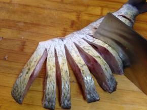 从腹部朝背部均匀地切条，要保证腹部相连不断