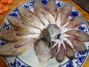 盘子底部铺上葱段、姜片，将切好的鱼条顺一个方向摆好，摆成孔雀开屏状，