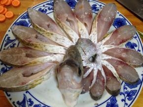 盘子底部铺上葱段、姜片，将切好的鱼条顺一个方向摆好，摆成孔雀开屏状，
