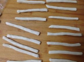 将小条搓成小棒，喷一点水（也可以不搓，直接粘芝麻造型，操作的时候，剩余的面片要加盖保鲜膜，以防其干裂）