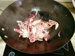 锅里倒入适量油烧热，下入鱿鱼翻炒