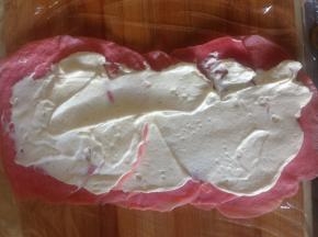 保鲜膜铺底  摊好的薄饼一层层叠压着摆齐  在中间抹上淡奶油  里面也可以卷一些水果或者果冻 左右的边往里折好  尽量一样齐