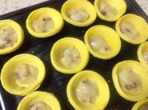 取出回温的蛋挞皮舀入适量的香蕉葡萄干泥