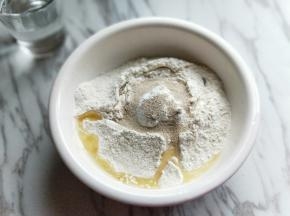 饼皮的全部食材加入容器中，(主料部分全部是饼皮食材)分次加入温水，因为不同的面粉吸水性不同。