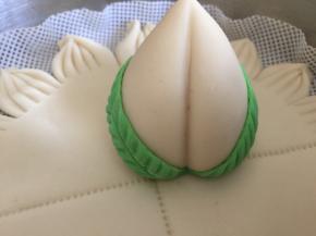 再用少许面团加适量的抹茶粉揉成绿色的面团，做出树叶的形状，依然用牛奶做粘稠剂，粘在桃子上。