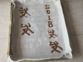 油纸上提前薄薄涮点油，然后把可可液裱出字体，送入烤箱预烤5分钟定型取出，再倒蛋糊（字体要反面写，这样卷起来才能显示正面，否则按正常写字，反面卷起字就反了）