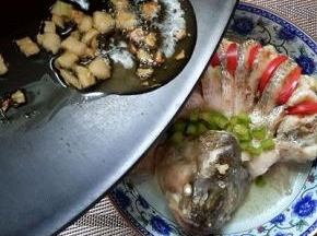 蒸好的鲈鱼会有很多汤汁，将汤汁倒出，红甜椒切丝，摆放再鱼背部切开处，绿甜椒切丁，放入鱼头和鱼背交接处，如图。
会后将炒香的热油淋再鱼身上即可。