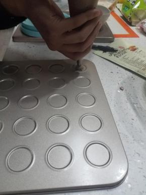 将面糊装入准备好的裱花袋，在烤盘中挤圆，全部挤好轻轻震盘。