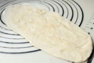 取一个面剂子，擀开成橄榄状，均匀抹上油酥。