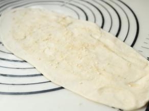 取一个面剂子，擀开成橄榄状，均匀抹上油酥。