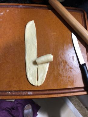 面团松弛好擀开，擀成椭圆形。翻面，用刮板把面团切开，然后把底边压薄。卷成玫瑰花形。