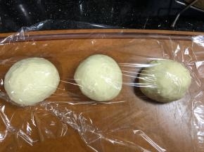 发酵完成将面团取出，排气，分割成9等份。滚圆，盖保鲜膜松弛20分钟。我这次用了两个模具。同时准备以下两项工作（忘记拍照了），模具薄薄抹上一层油，白芝麻和低分混合备用。