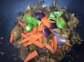 看锅中的汤汁让鸡肉快吸收，剩下不多时，下入青椒、胡萝卜和洋葱翻炒几下
