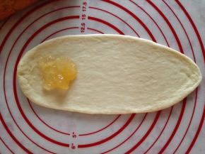 6.	取一个面团擀成牛舌状，一端放入适量果酱，