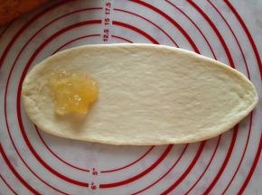 6.	取一个面团擀成牛舌状，一端放入适量果酱，