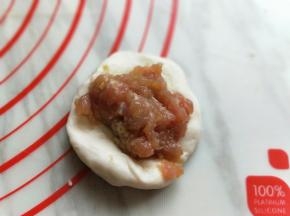 取一块面团，用掌心压扁，放入肉馅。