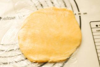 松弛之后的派皮取出来，均匀分成四份。每一份都上下垫保鲜膜擀平比模具略大。